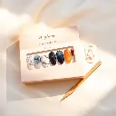 A flat-lay photo of a dreamy semi-cured gel nail strip set in a soft beige and peach box labeled 'Heyhae – Dreaming of You', featuring celestial-inspired designs with golden stars, deep blue, marble white, and warm.webp