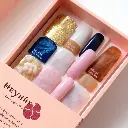 Surreal infrared tones. Flat lay of semi-cured gel nail strips in a beige and peach 'Heyhae – Dreaming of You' box. Celestial designs in gold, deep blue, marble white, and brown. Vibrant colors, light streaks, othe.webp