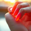 An extreme macro close-up of a sculpted clay model of a hand with sunset ombre gel nails transitioning from orange to pink, glowing under golden hour sunlight. The image emphasizes small subject details, modeled sh.webp