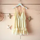 Gentle, soft light in surreal infrared tones. A soft beige rayon, cotton, and sheer mesh halter mini dress with a deep V-neckline, tie-back straps, and ruffled polka-dot hem hangs on a rustic wood wall with coastal.webp